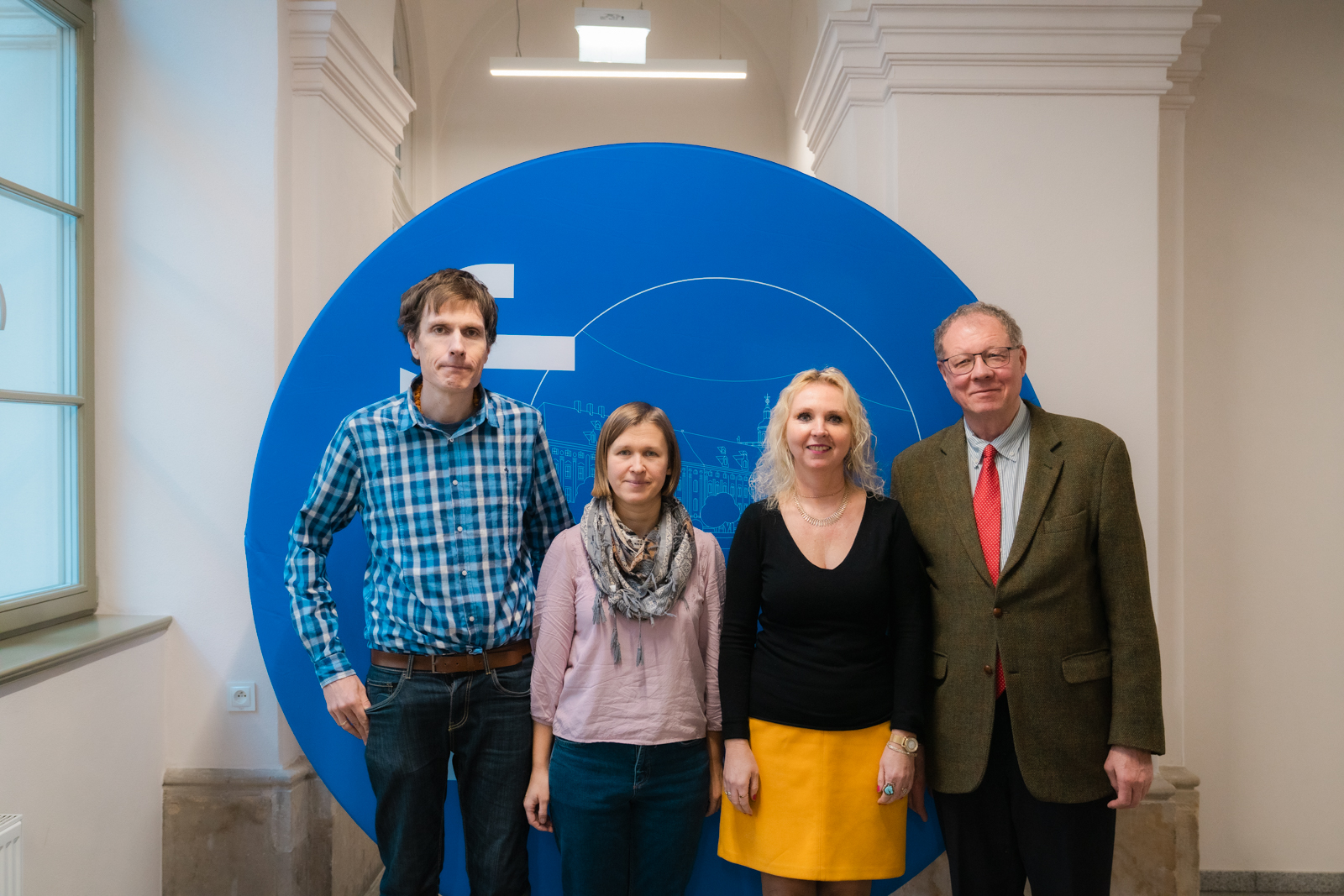 grupa osób stojąca na tle okrągłej, niebieskiej ścianki z logo Uniwersytetu Wrocławskiego