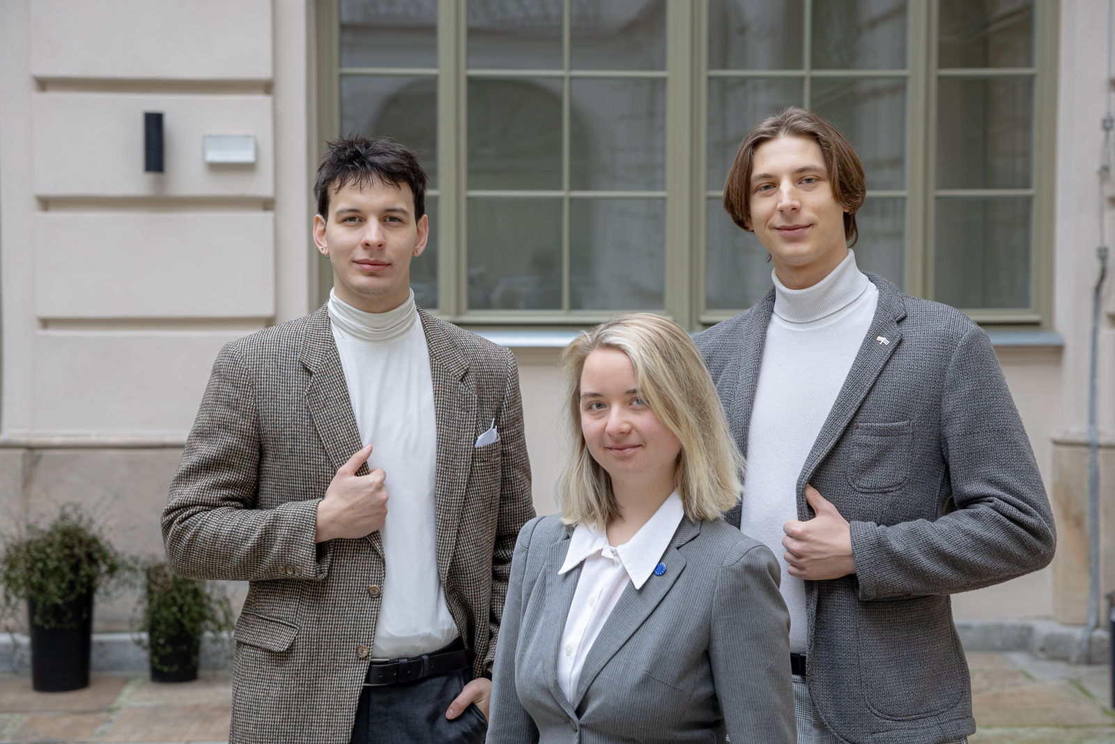 zdjęcie przedstawiające trzech studentów ubranych wizytowo, znajdujących się na patio